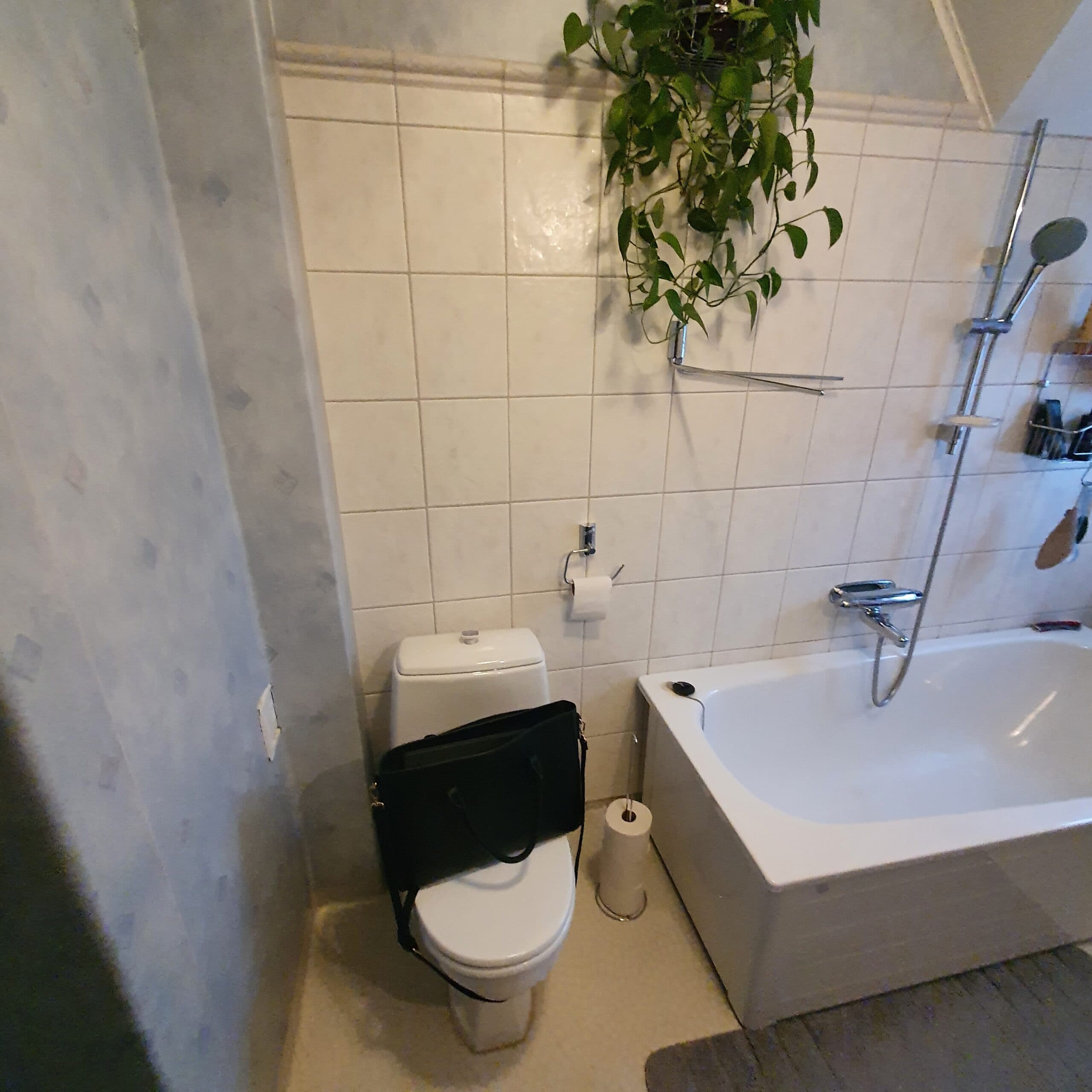 Stilrent badrum med vitt kakel, duschhörna med vikbara glasväggar och modernt handfat med förvaring.