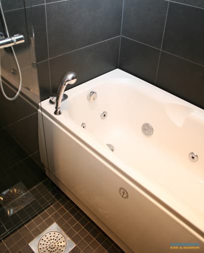 Badrum med belysta nischer i svart mosaik