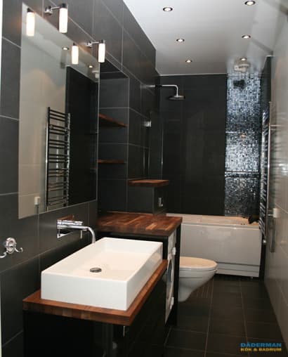 Badrum med belysta nischer i svart mosaik