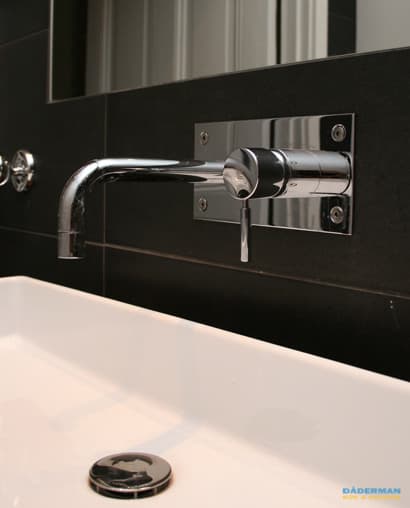 Badrum med belysta nischer i svart mosaik