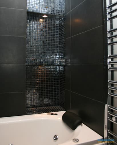 Badrum med belysta nischer i svart mosaik