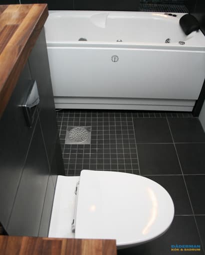 Badrum med belysta nischer i svart mosaik