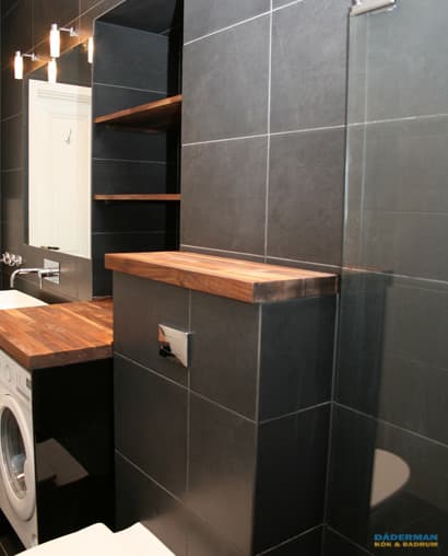 Badrum med belysta nischer i svart mosaik