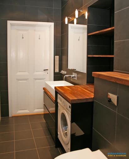 Badrum med belysta nischer i svart mosaik