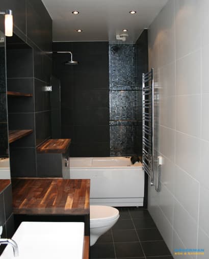 Badrum med belysta nischer i svart mosaik