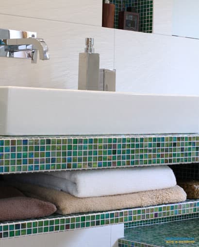 Lyxigt badrum med grön glasmosaik som detalj