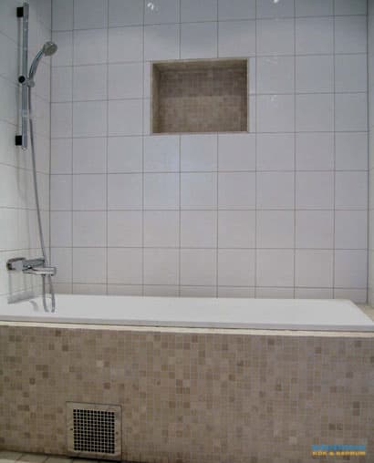 Badrum med vitt kakel och beiget klinker