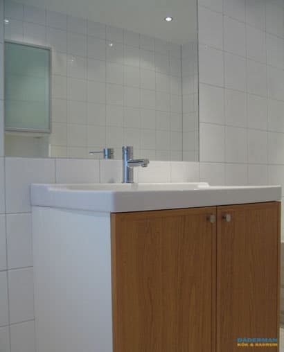 Badrum med vitt kakel och beiget klinker