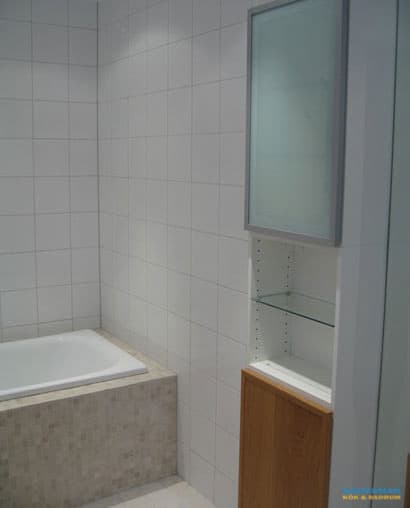 Badrum med vitt kakel och beiget klinker