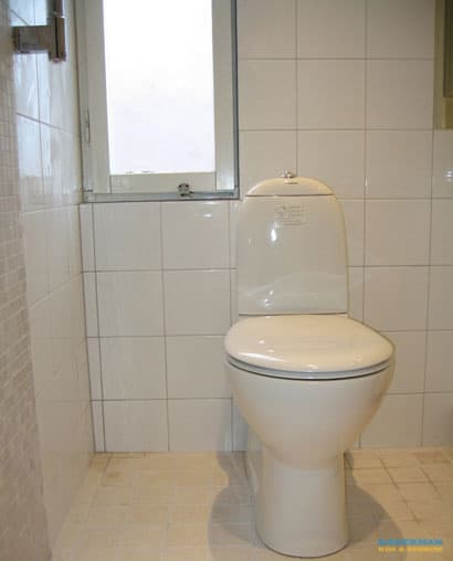 Badrum med vitt kakel och beiget klinker