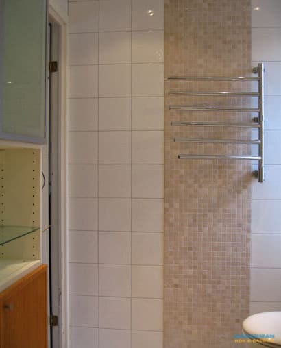 Badrum med vitt kakel och beiget klinker