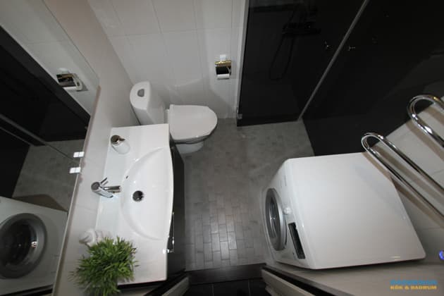 Badrum med vitt kakel och grå klinker