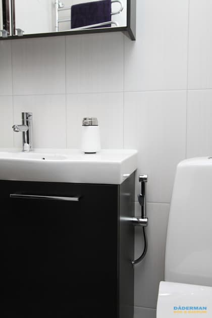 Badrum med vitt kakel och grå klinker