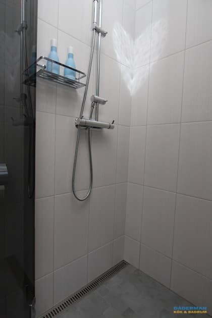 Badrum med vitt kakel och grå klinker