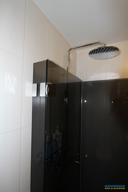 Badrum med vitt kakel och grå klinker