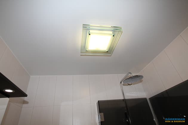 Badrum med vitt kakel och grå klinker