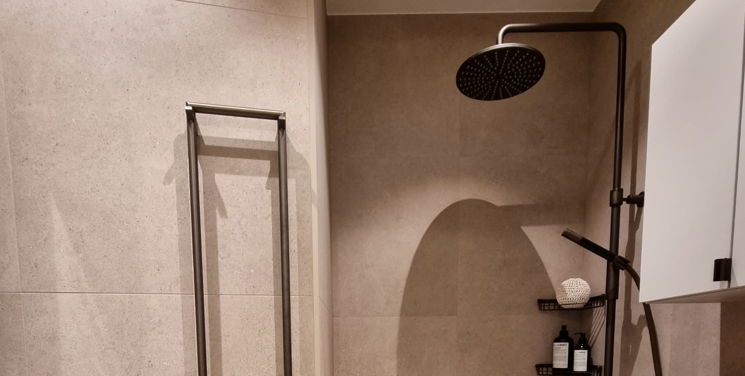 Svart vattenfallsdusch i nyrenoverat badrum med beige kakel