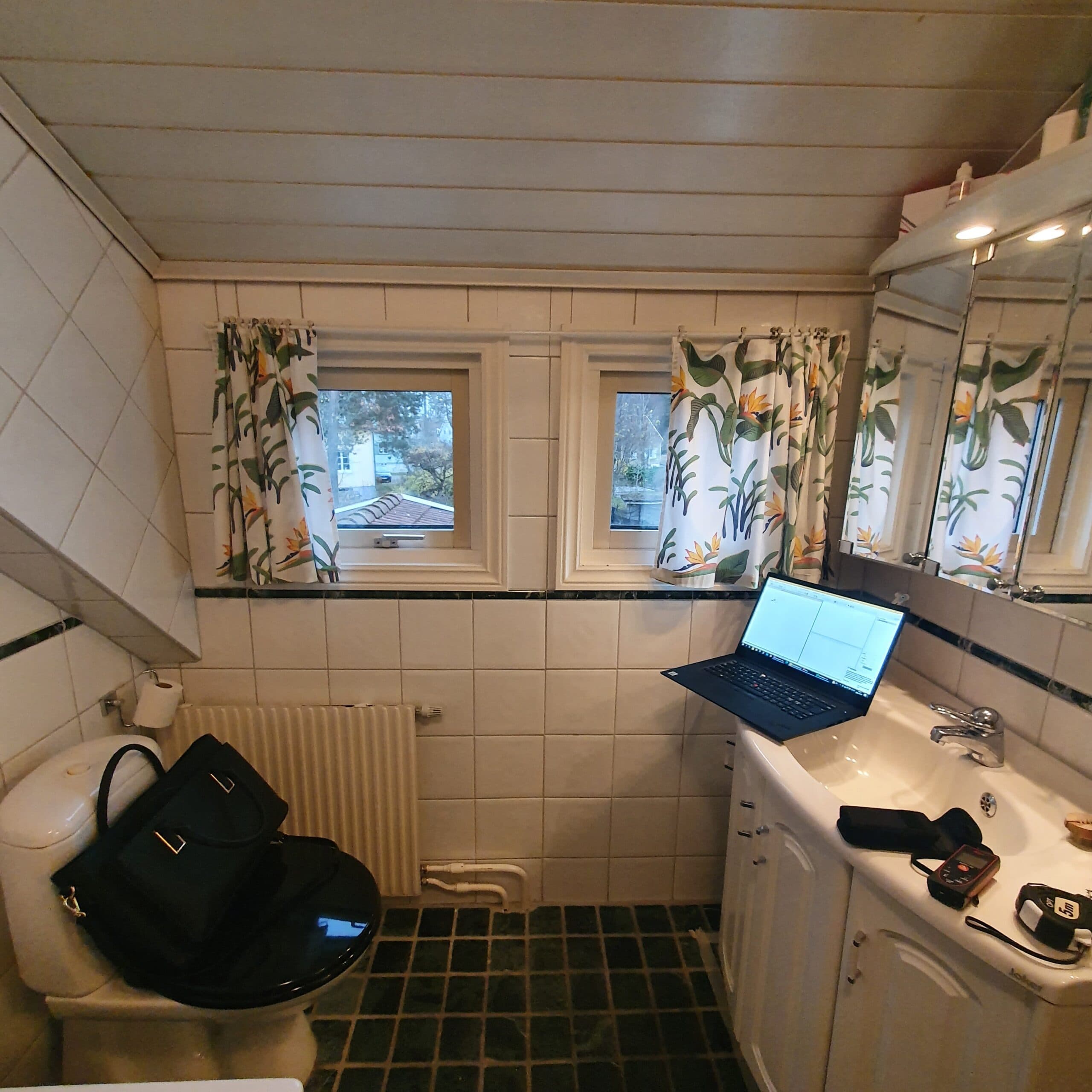 Badrum före renovering med äldre kakel, duschdraperi och traditionell inredning.