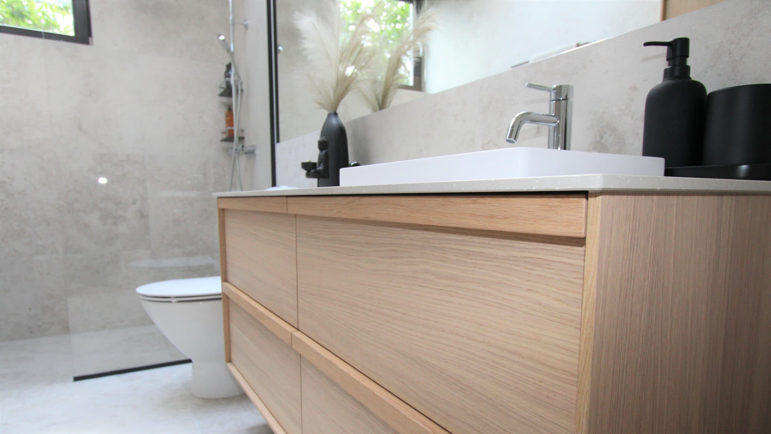 Elegant badrum med toalett, svart duscharmatur och stora ljusa kakelplattor