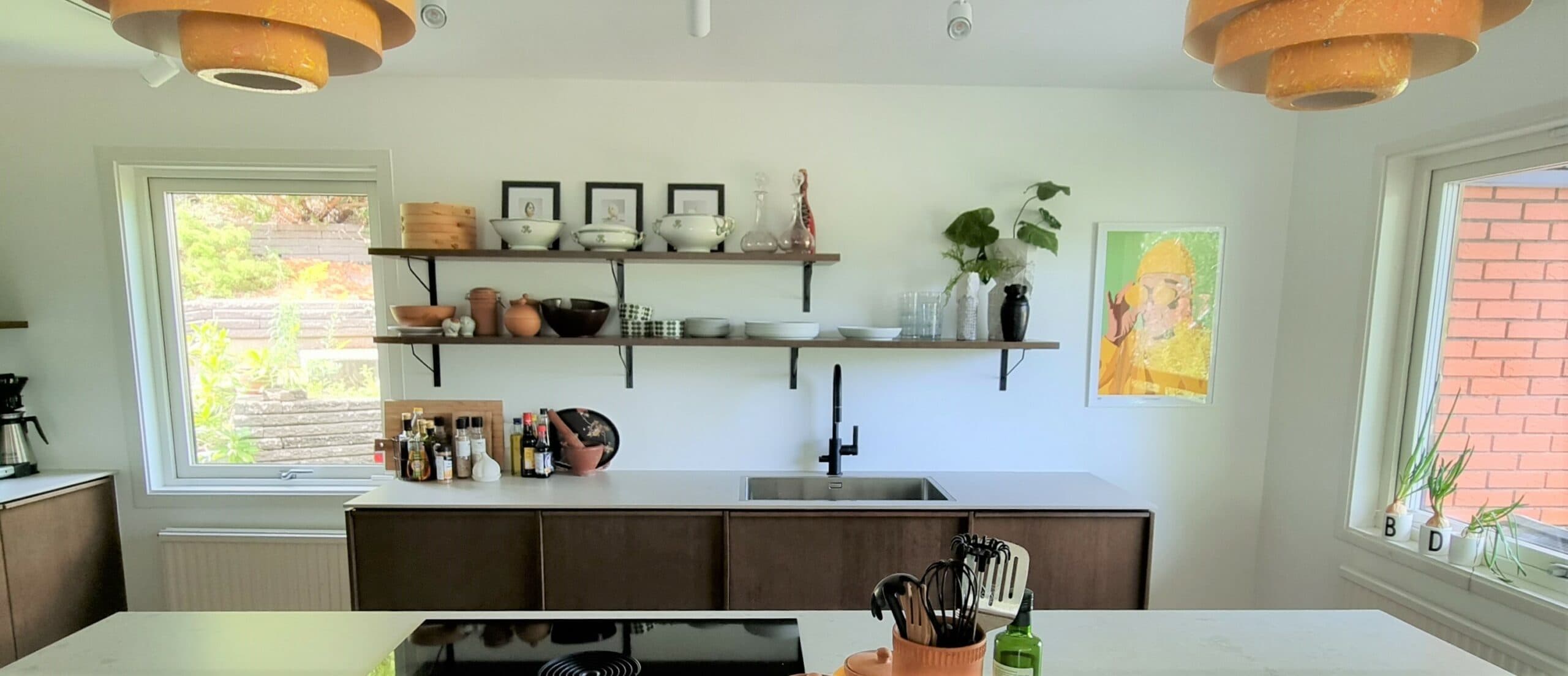 Köksrenovering med mörka skåp, ljus stenskiva, öppen hyllförvaring och spotlights i taket