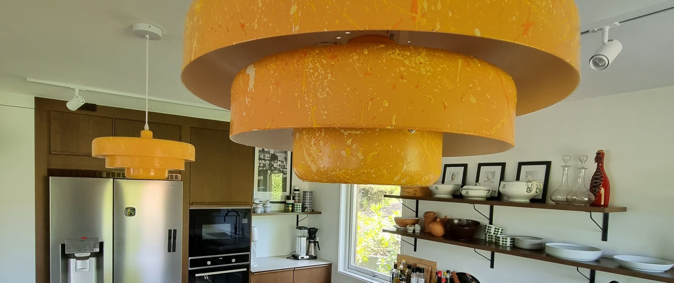 Helbild av renoverat kök med vita skåpluckor, svart bänkskiva, grått kakel och integrerad spis