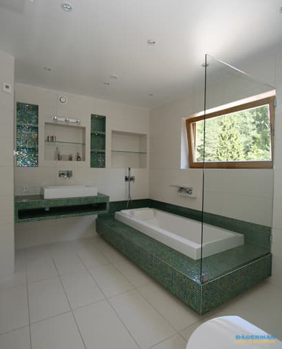 Lyxigt badrum med grön mosaik, inbyggt badkar, väggmonterad blandare och träfönster