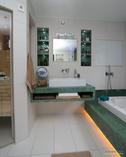 Lyxigt badrum med grön mosaik, fristående badkar, bastu och integrerad belysning
