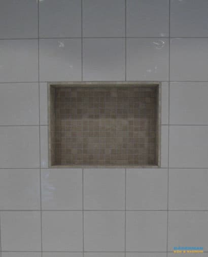 Badrum med vitt kakel och beiget klinker