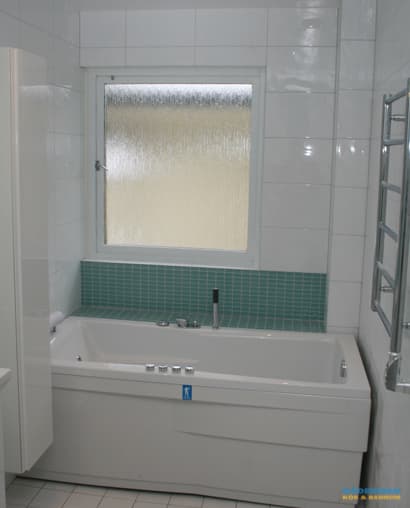 Badrum med vitt kakel och blå glasmosaik