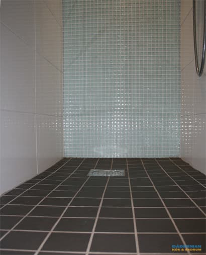 Badrum med blå mosaik och vitt kakel