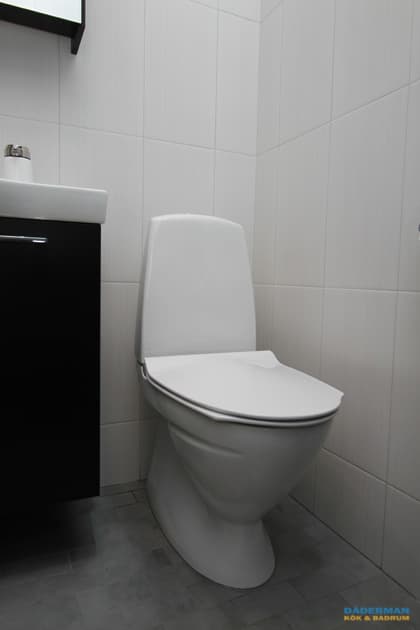 Badrum med vitt kakel och grå klinker