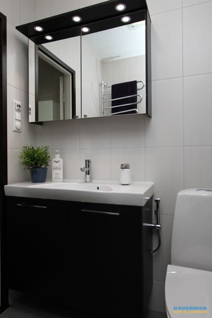 Badrum med vitt kakel och grå klinker