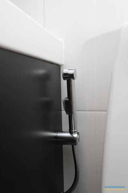 Badrum med vitt kakel och grå klinker